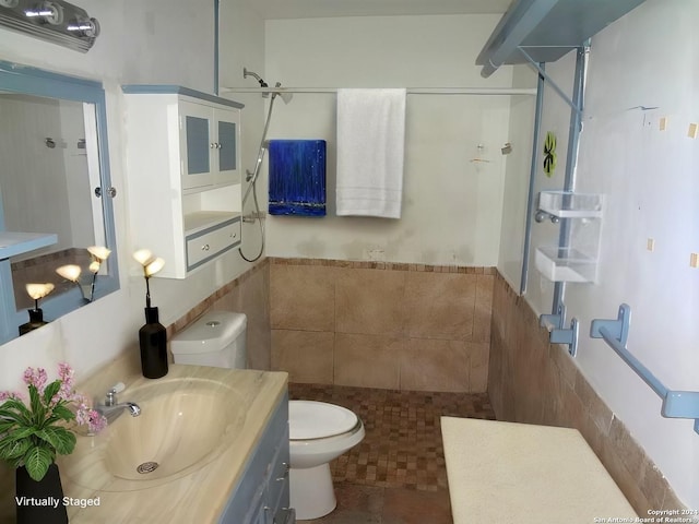 bathroom featuring walk in shower, vanity, tile walls, tile patterned flooring, and toilet