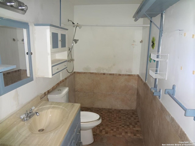 bathroom featuring vanity, toilet, tile walls, and walk in shower