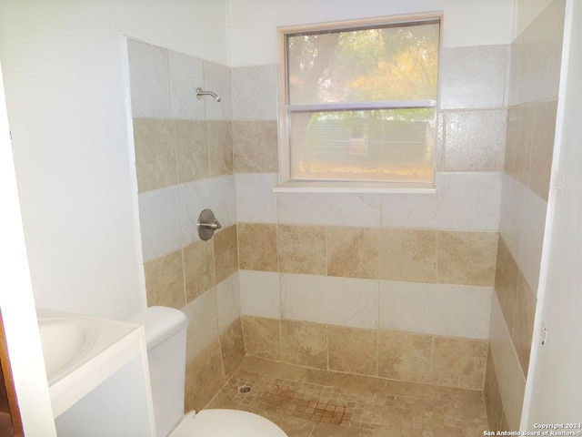 bathroom with tiled shower, vanity, and toilet