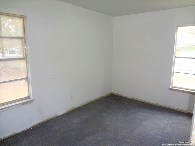 unfurnished room featuring dark carpet