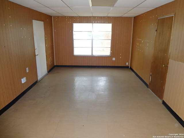 unfurnished room with radiator, a drop ceiling, and wood walls