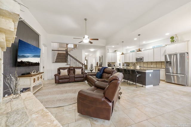 living room with light tile patterned floors, ceiling fan, and sink