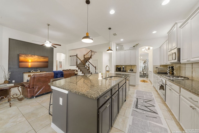 kitchen featuring backsplash, white cabinetry, sink, and a center island with sink