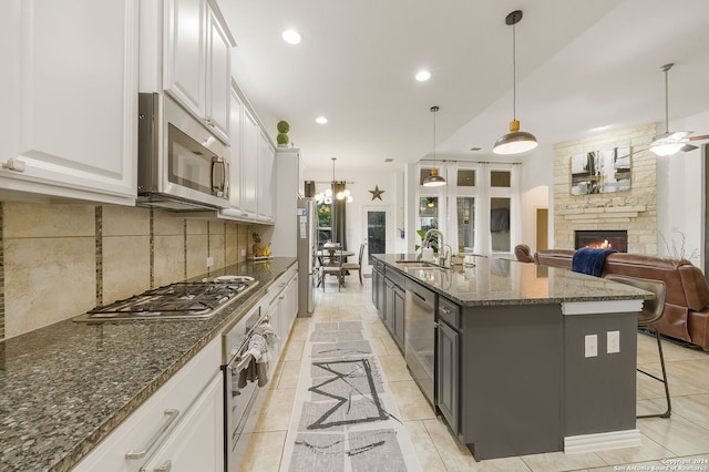 kitchen with white cabinets, a breakfast bar, a center island with sink, and appliances with stainless steel finishes