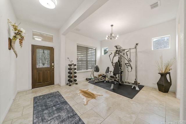 workout area featuring light tile patterned flooring, a healthy amount of sunlight, and a notable chandelier