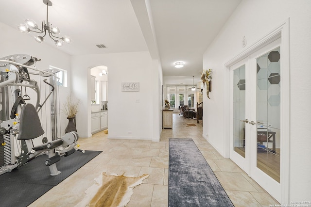 exercise area featuring a chandelier, french doors, and a healthy amount of sunlight