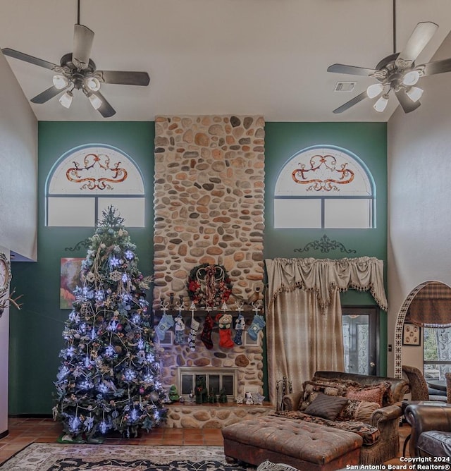 unfurnished living room with a fireplace, a high ceiling, and ceiling fan