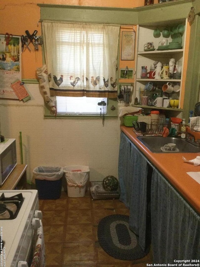 kitchen featuring white range, tile walls, and sink