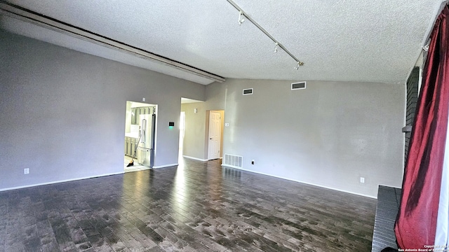 empty room featuring a textured ceiling, dark wood-type flooring, and vaulted ceiling