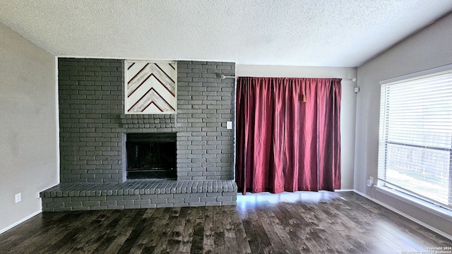 unfurnished living room featuring a textured ceiling, a fireplace, wood-type flooring, and plenty of natural light