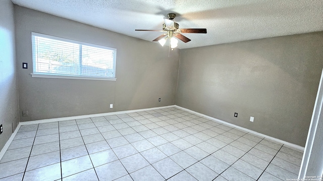 empty room with ceiling fan, light tile patterned floors, and a textured ceiling