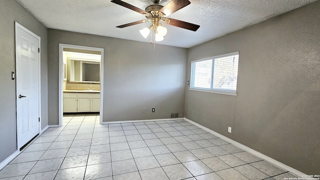 tiled spare room featuring a textured ceiling, ceiling fan, and sink