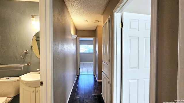 hallway with dark hardwood / wood-style floors, sink, and a textured ceiling