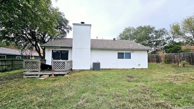 back of house featuring central air condition unit and a lawn