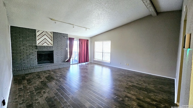 unfurnished living room featuring vaulted ceiling with beams, a fireplace, dark wood-type flooring, and a textured ceiling