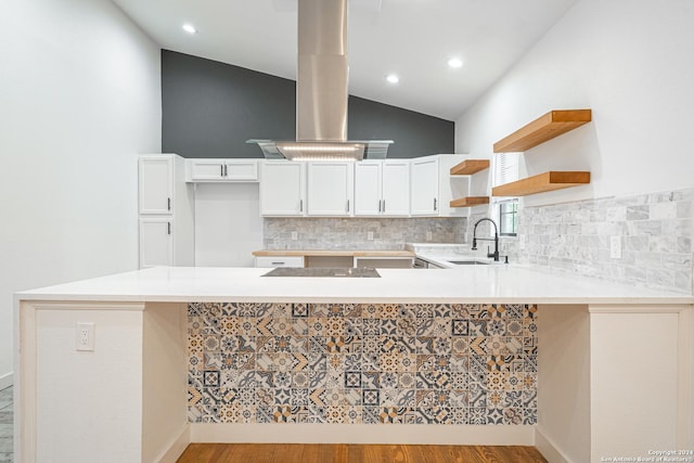 kitchen featuring kitchen peninsula, light wood-type flooring, white cabinetry, and vaulted ceiling