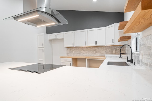 kitchen featuring island exhaust hood, backsplash, black cooktop, sink, and white cabinetry