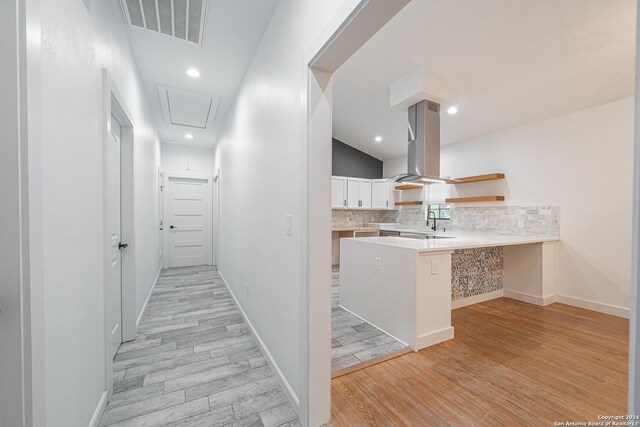 corridor with vaulted ceiling, sink, and light hardwood / wood-style flooring