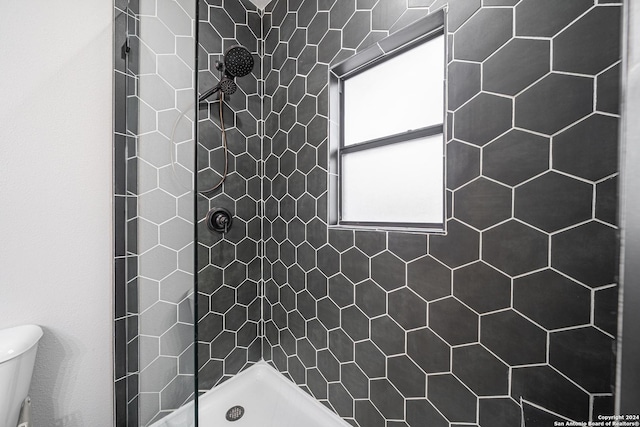 bathroom featuring a tile shower and toilet