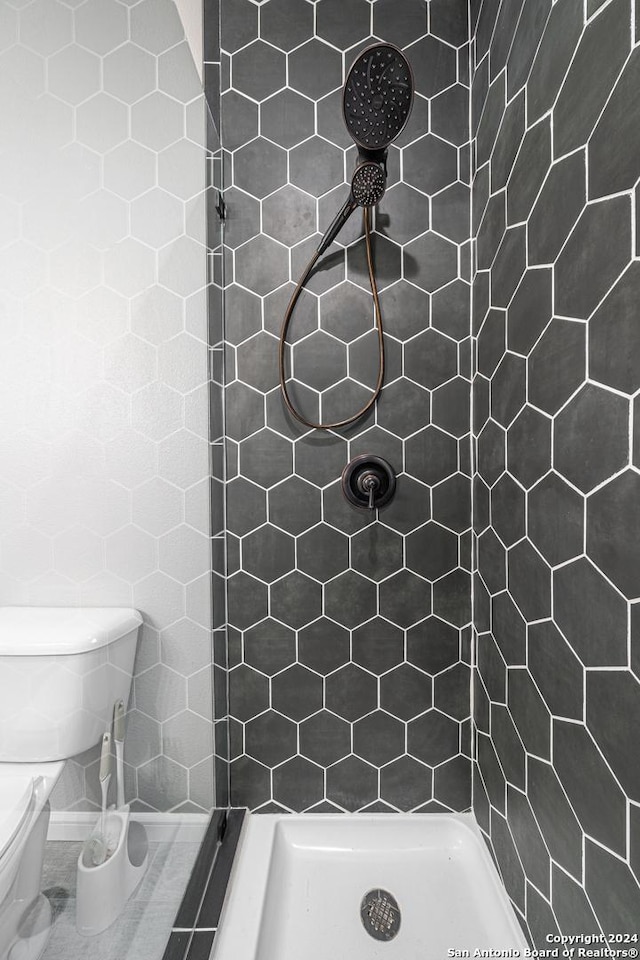 bathroom featuring a tile shower and toilet