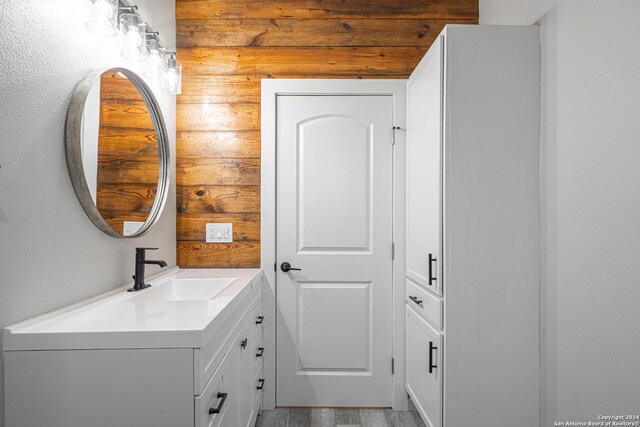 bathroom with hardwood / wood-style flooring, vanity, and wood walls