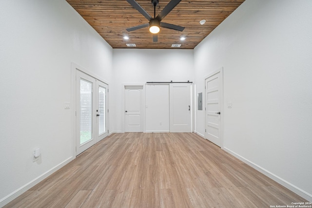 empty room featuring ceiling fan, french doors, a barn door, light hardwood / wood-style floors, and wood ceiling