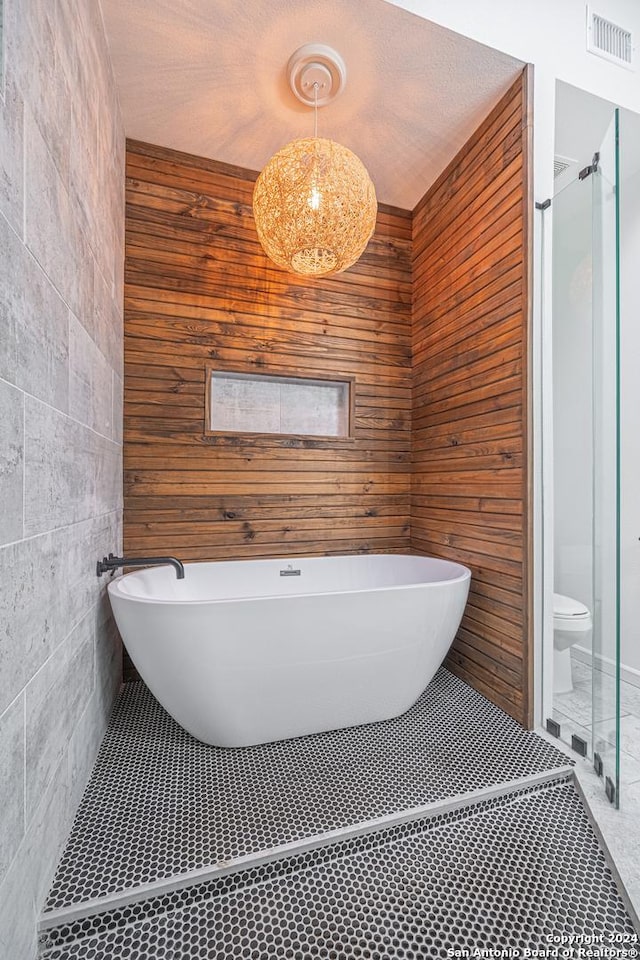 bathroom featuring tile patterned floors, wood walls, toilet, and tile walls