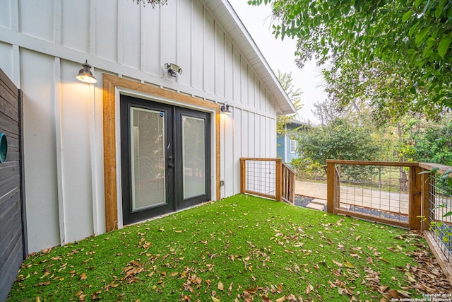 view of exterior entry with a yard and french doors