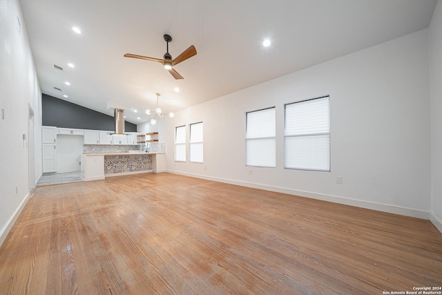 unfurnished living room with light hardwood / wood-style flooring, high vaulted ceiling, and ceiling fan with notable chandelier