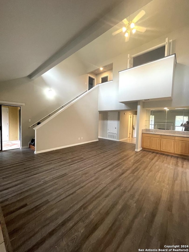 unfurnished living room featuring beamed ceiling, ceiling fan, dark wood-type flooring, and high vaulted ceiling