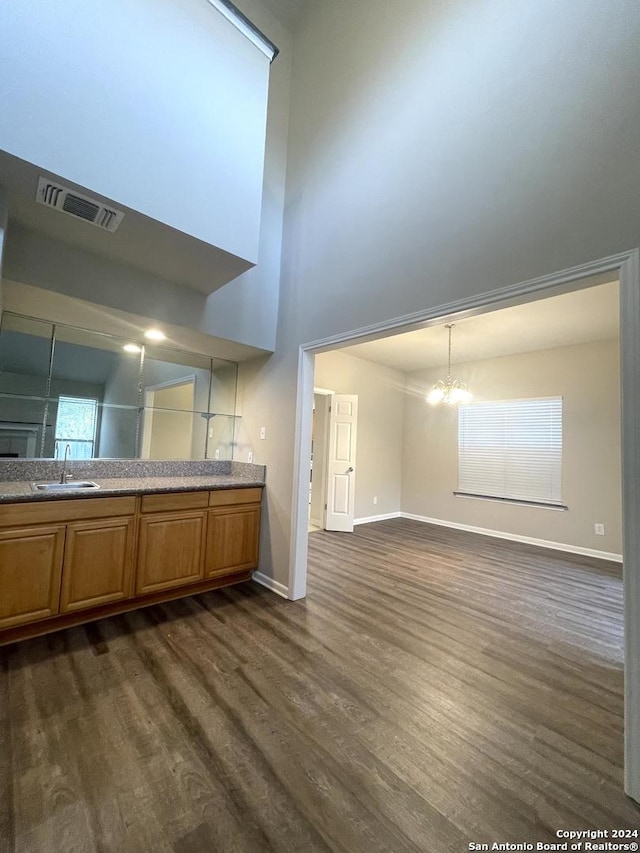 kitchen featuring sink, dark hardwood / wood-style floors, a notable chandelier, a towering ceiling, and pendant lighting