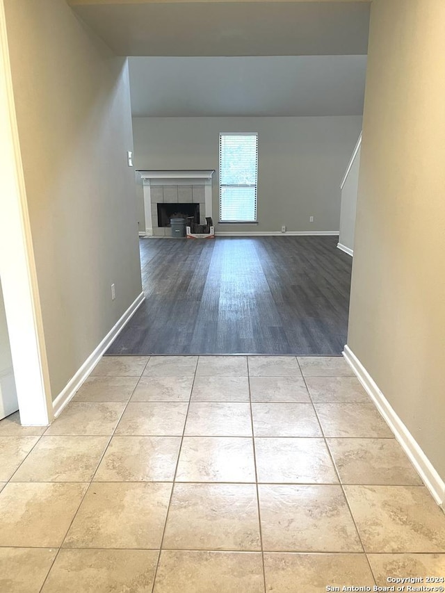 unfurnished living room with light hardwood / wood-style floors and a tiled fireplace