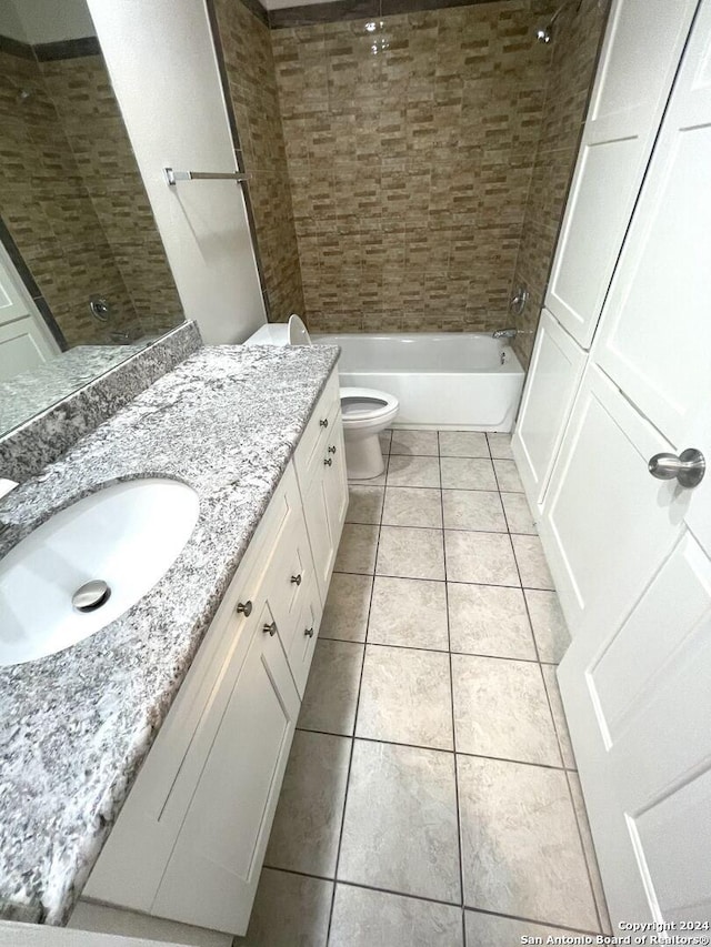 full bathroom with tile patterned floors, vanity, tiled shower / bath combo, and toilet