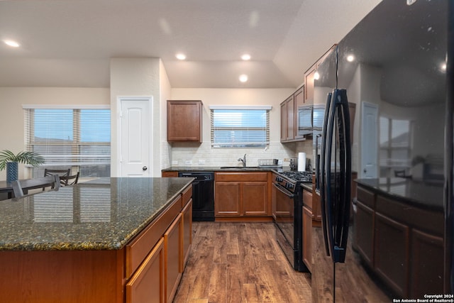 kitchen featuring tasteful backsplash, sink, black appliances, dark hardwood / wood-style floors, and a kitchen island