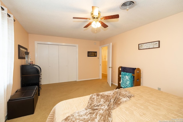 carpeted bedroom with ceiling fan, a closet, and a textured ceiling