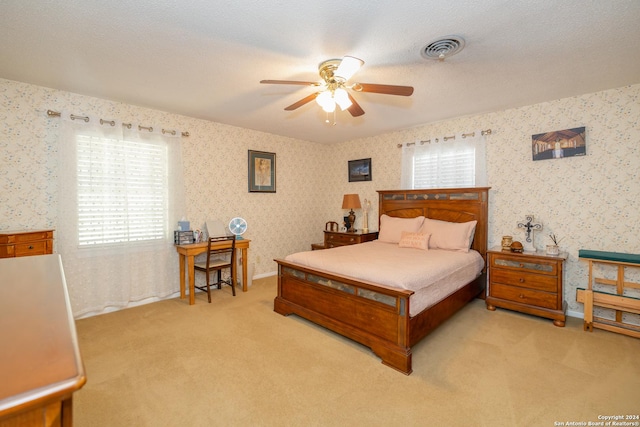 bedroom with a textured ceiling, ceiling fan, and light carpet