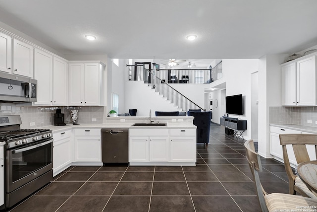 kitchen featuring stainless steel appliances, ceiling fan, sink, dark tile patterned flooring, and white cabinets