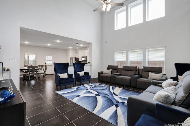 living room with ceiling fan, dark tile patterned floors, and a high ceiling