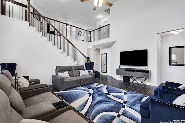 tiled living room with ceiling fan and a high ceiling