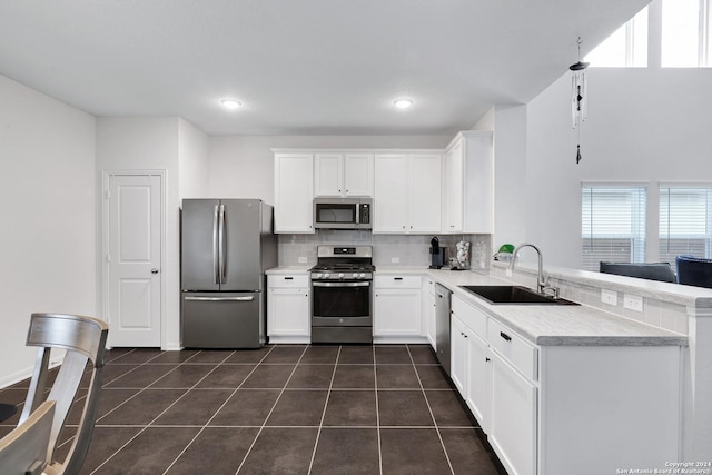 kitchen with white cabinetry, sink, stainless steel appliances, and dark tile patterned flooring