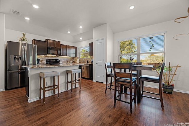 kitchen with dark hardwood / wood-style flooring, a breakfast bar, dark brown cabinets, black appliances, and a kitchen island