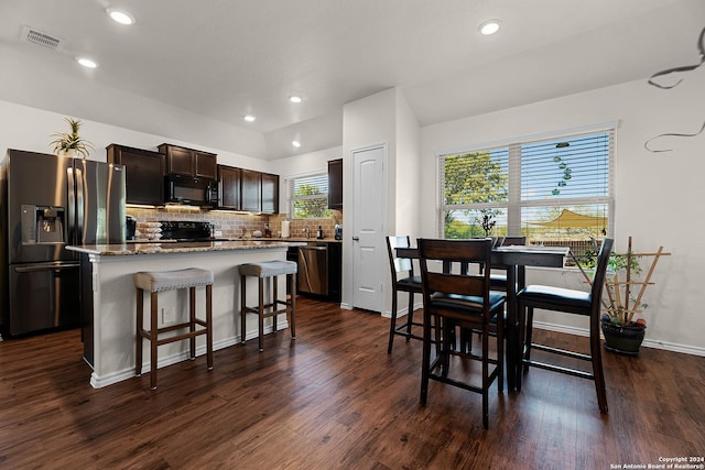 kitchen with dark brown cabinetry, dark hardwood / wood-style flooring, a kitchen bar, a kitchen island, and black appliances