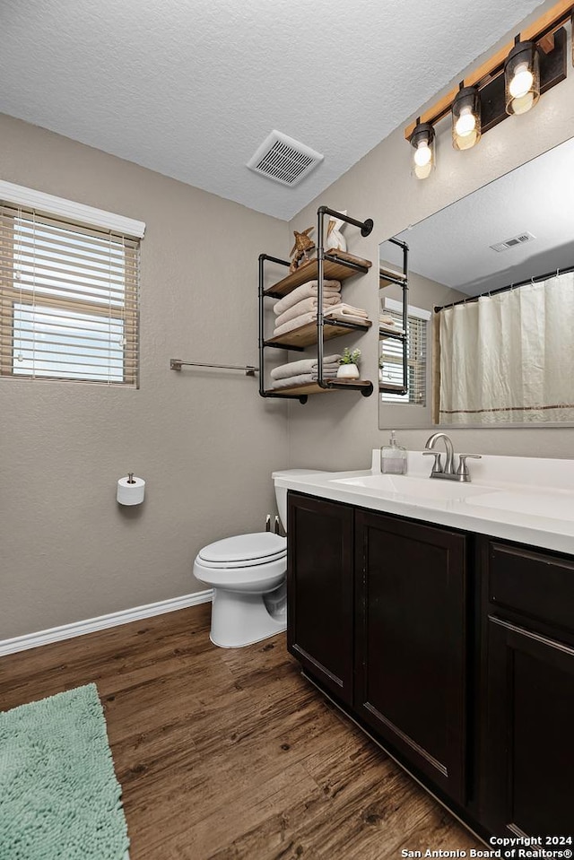 bathroom featuring a textured ceiling, vanity, hardwood / wood-style flooring, and toilet