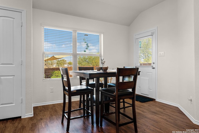 dining space with dark wood-type flooring and vaulted ceiling