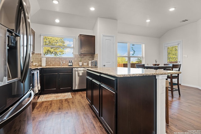 kitchen featuring a healthy amount of sunlight, a kitchen island, lofted ceiling, and appliances with stainless steel finishes