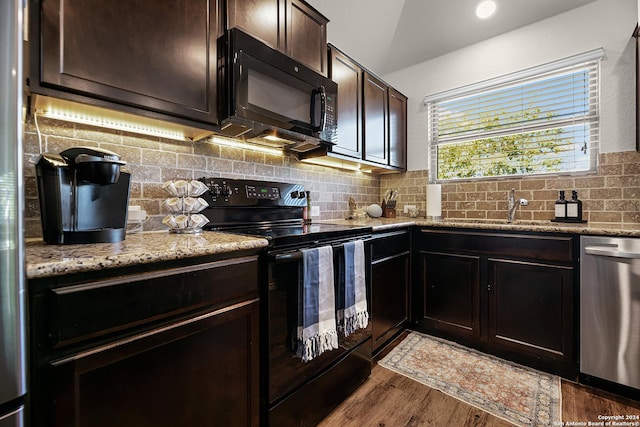 kitchen with backsplash, light stone countertops, dark wood-type flooring, and black appliances