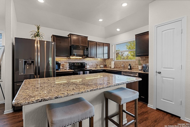 kitchen featuring dark brown cabinets, a center island, dark hardwood / wood-style floors, and black appliances