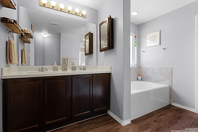 bathroom with a bathing tub, hardwood / wood-style floors, and vanity