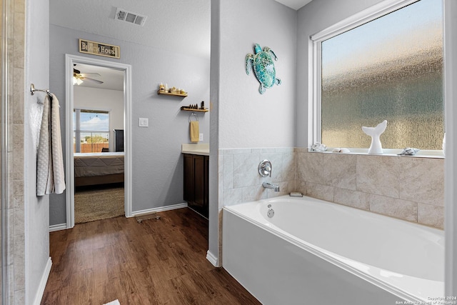 bathroom featuring hardwood / wood-style flooring, ceiling fan, a tub, and vanity