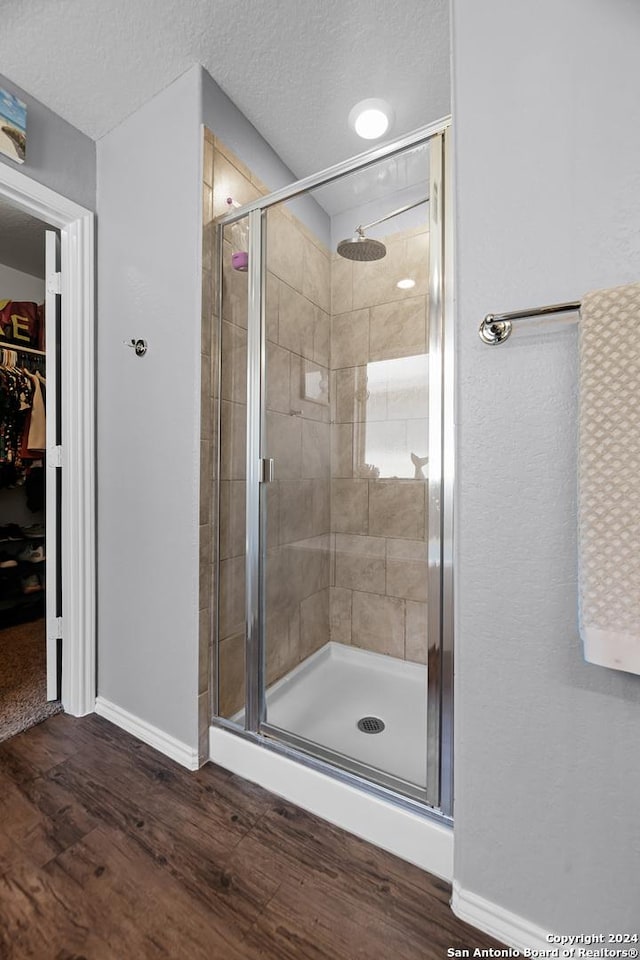 bathroom with wood-type flooring, a textured ceiling, and a shower with shower door